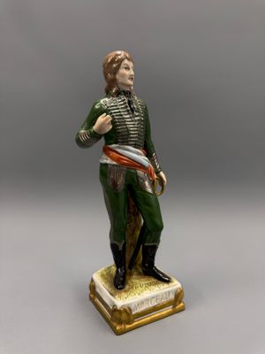 une figurine ancienne représentant un homme muni d'une épée, posée sur un socle