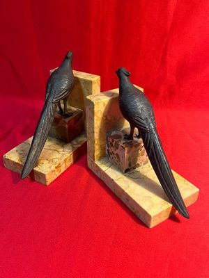 paire de serre-livres représentant des oiseaux noirs sur un socle en marbre, sur fond rouge
