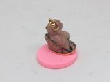 a small figurine of a monkey sitting on a pink base