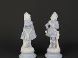 two white figurines of a man and a woman on a pedestal