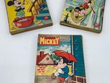 trois livres de Mickey Mouse posés sur une table blanche