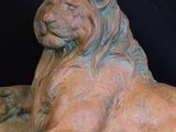 statue of a lion resting on a rock on a black background