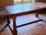 a wooden table in a room with a brick floor