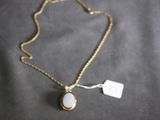 a close up of a gold necklace with a white stone on it