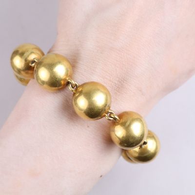 gold ball bracelet on a woman ' s hand