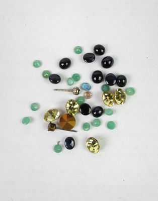 some black and green beads and gold bells on a white surface