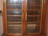 un meuble en bois avec des portes en verre dans le coin d'une pièce