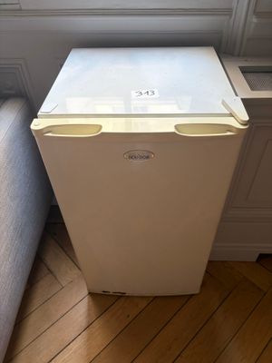 un petit réfrigérateur blanc dans le coin d'une pièce