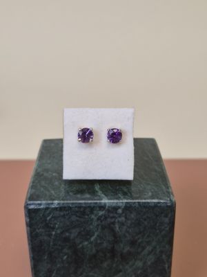 une paire de boucles d'oreilles en améthorate posées sur un bloc de marbre