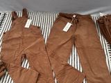 trois paires de pantalons marron posées sur une couverture rayée