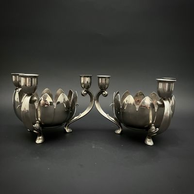paire de bougeoirs plaqués argent sur un socle, sur fond noir