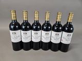 six bottles of red wine lined up in a row on a table