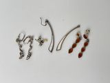 trois paires de boucles d'oreilles et un crochet posés sur une surface blanche