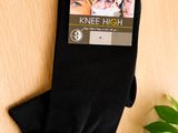 black knee high socks on a wooden surface with a plant in the background