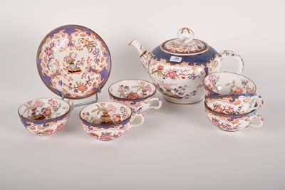 a tea pot, cups and saucer set on a table