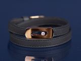 bracelet en cuir noir avec un fermoir plaqué or sur fond bleu