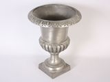 un vase en argent posé sur une surface blanche