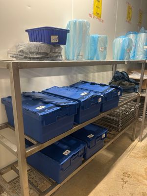 une étagère métallique sur laquelle sont posées des boîtes bleues, dans une pièce