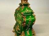 a green vase with a gold decoration on it