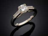 an engagement ring with a diamond and baguets on a black background