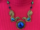 a close up of a woman wearing a red sweater and a blue necklace