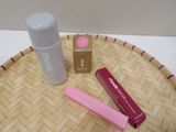 a bottle of lip balm, a tube of lip balm, and a tube of lip balm on a wicker tray