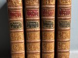 quatre vieux livres sont alignés sur une étagère adossée au mur