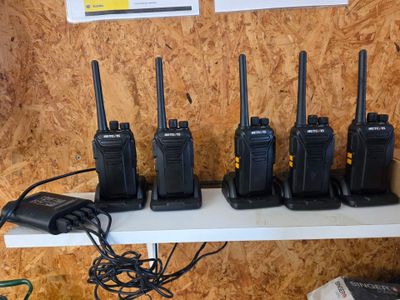Plusieurs talkies-walkies sont alignés sur une étagère dans une pièce
