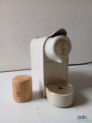 une cafetière blanche avec un couvercle en bois, posée à côté d'une tasse