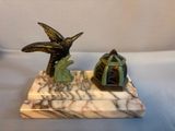 a small statue of a bird on a marble base
