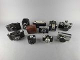 an assortment of old cameras sitting on top of a white surface