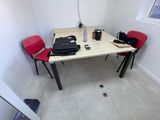 a table with two red chairs and a laptop on it