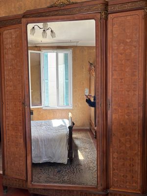 une personne en train de prendre une photo d'une chambre à coucher équipée d'un grand miroir