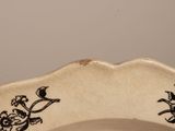 a black and white plate with a bird and flowers on it