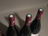 three bottles of red wine sit on a counter top next to a bottle of wine