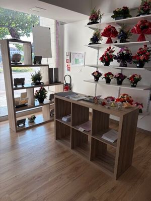 a room with a table, shelves, and flowers on the wall