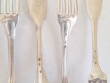 four forks and a knife on a white surface