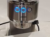 a silver coffee maker with a blue light on it