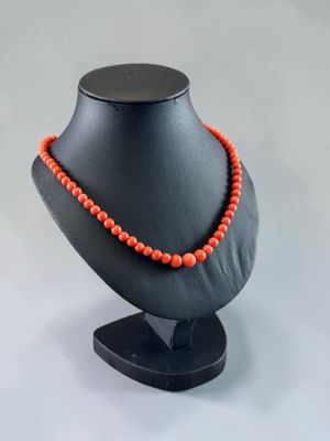 a black mannequin with a red beaded necklace on it