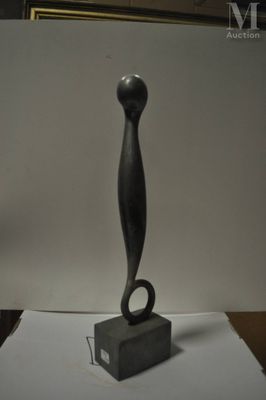une sculpture noire posée sur une table, avec une photo en arrière-plan