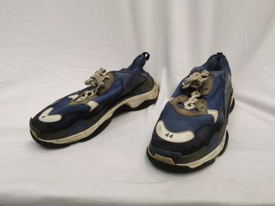 deux paires de baskets bleues et blanches posées sur une surface blanche