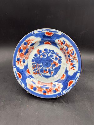a close up of a blue and white plate with red flowers on it