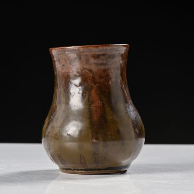 un vase marron posé sur une table sur fond noir