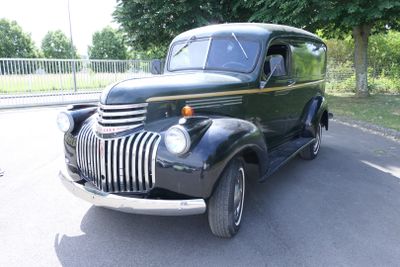 an old black truck parked on the side of the road