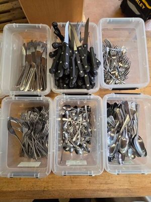 a lot of silverware in plastic containers on a table