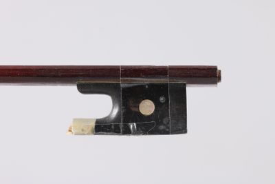 un gros plan d'un archet de violon posé sur une surface blanche
