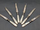 six knives are lined up in a circle on a table