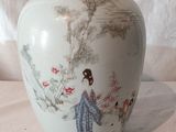 un vase blanc avec un tableau sur une table