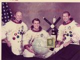 Deux hommes vêtus de combinaisons spatiales blanches posent pour une photo avec un globe terrestre