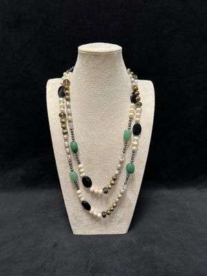 a white mannequin necklace with black and green beads